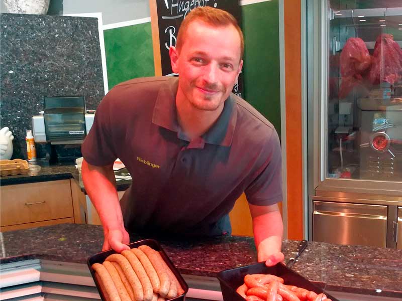 Ein freundlicher Mitarbeiter der Metzgerei Rieblinger bei der Arbeit