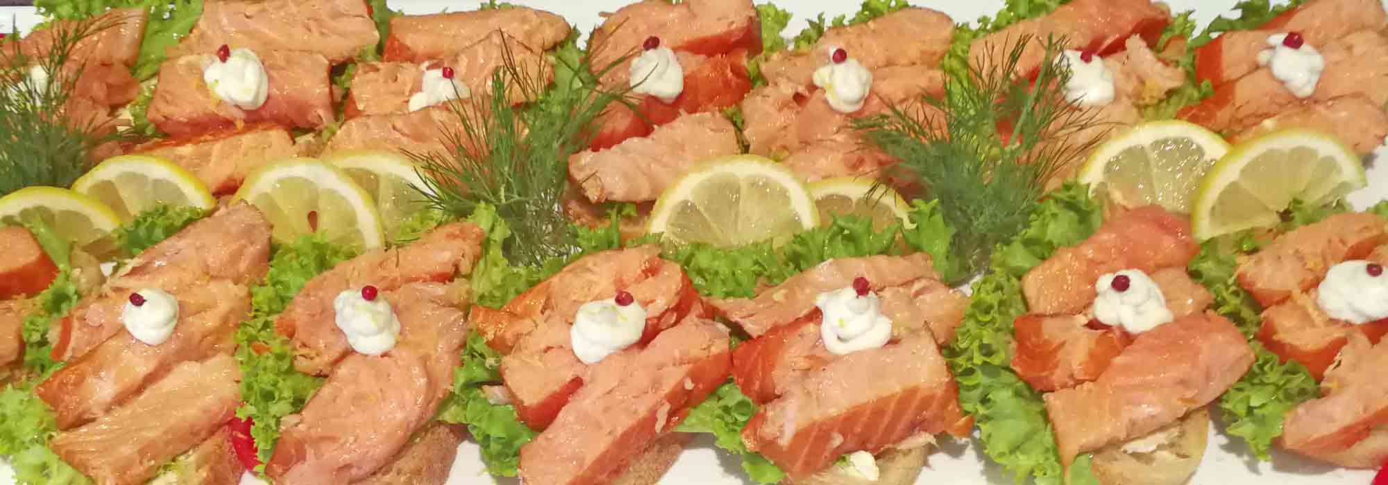 Festlich dekorierte Fischplatte unseres Partyservices mit Räucherlachs und Beilagen